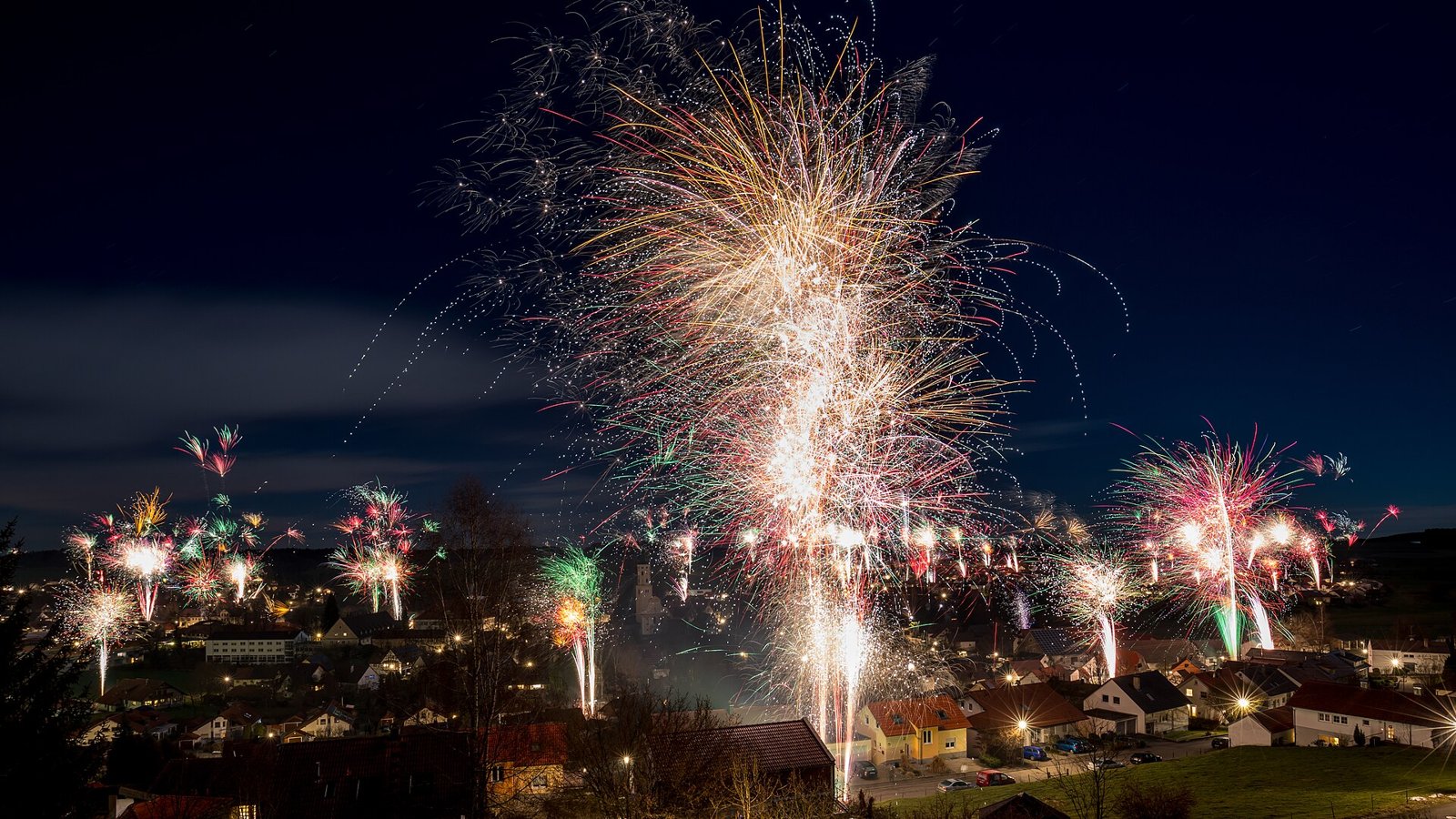 Feux d'artifice éclatant dans le ciel nocturne au-dessus d'un village le soir du Nouvel An